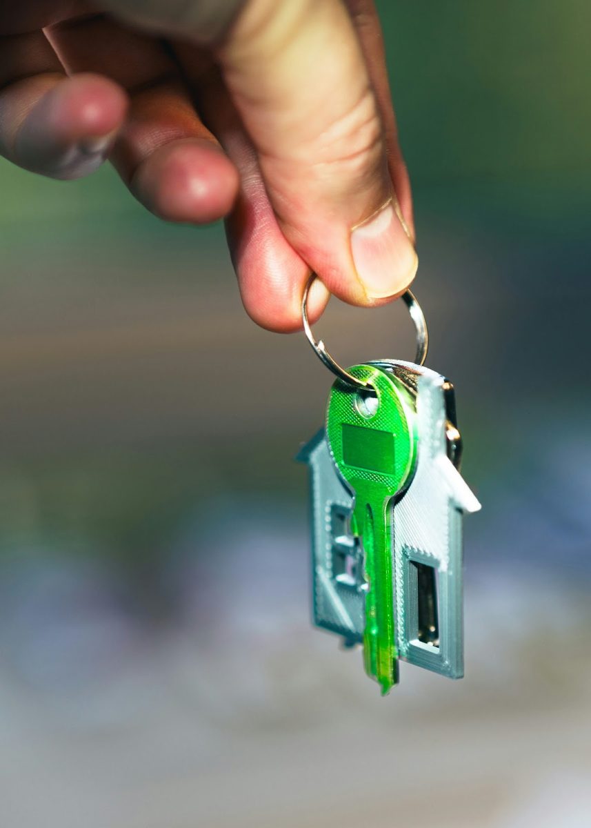 Une main tenant une clé verte d’une maison